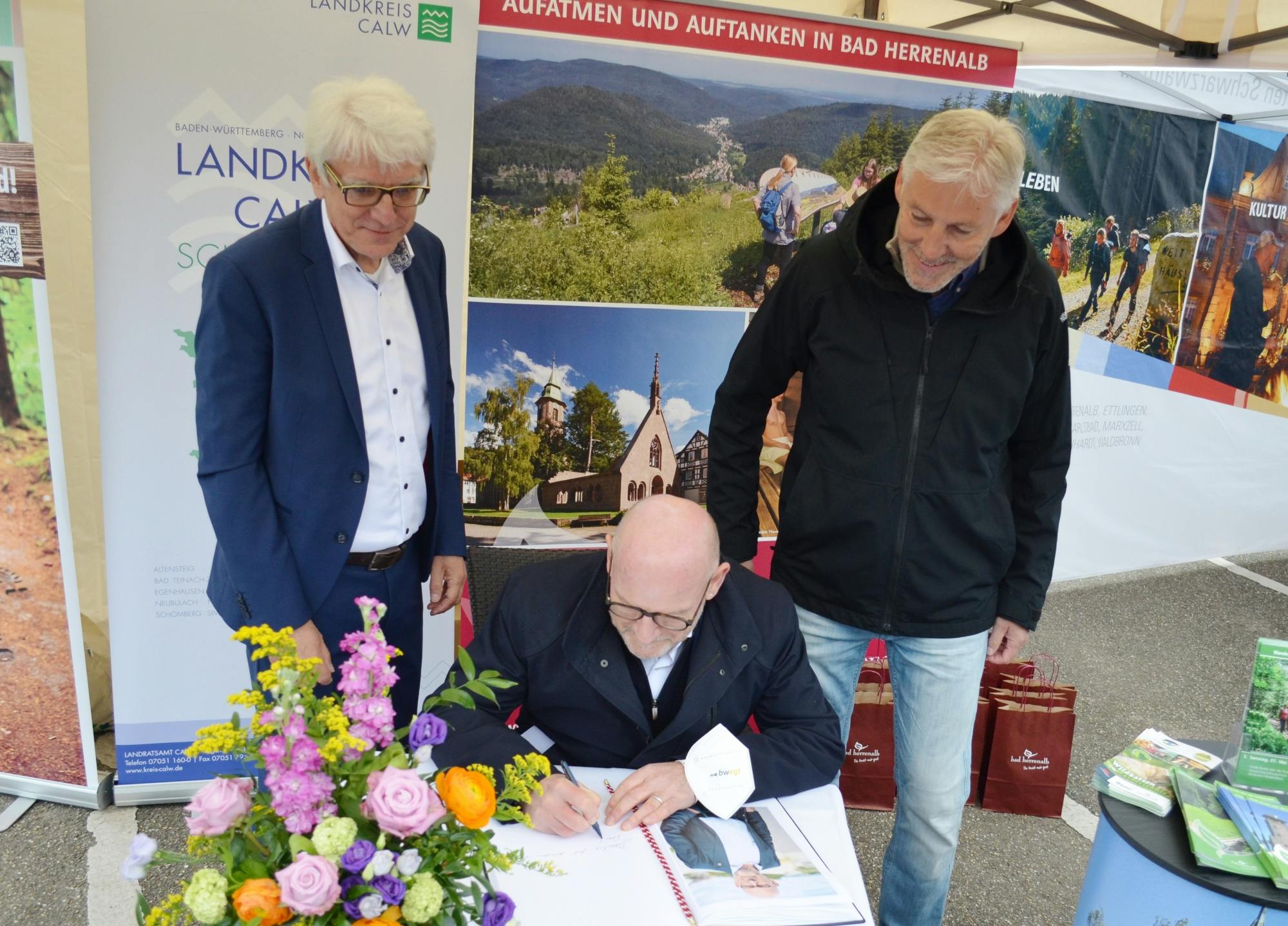 Eingerahmt von Bürgermeister Klaus Hoffmann und Landrat Helmut Riegger trägt sich Verkehrsminister Winfried Herrmann in das Goldene Buch der Stadt ein.